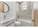 Bright bathroom with marble-esque tiled shower and a round vanity mirror at 102 Arrow Ln, Rotonda West, FL 33947