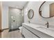 Modern bathroom featuring double vanity, round mirrors, and a glass-enclosed shower at 102 Arrow Ln, Rotonda West, FL 33947