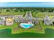 Aerial view of community pool, clubhouse, and nearby homes surrounded by lush greenery and a scenic pond at 12664 Oak Hill Way, Parrish, FL 34219