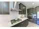Close-up of kitchen with stainless steel hood, gas cooktop, white subway tile backsplash, and dark cabinets at 12664 Oak Hill Way, Parrish, FL 34219