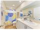 Bathroom with a double sink vanity, decorative mirror, and shower/tub with blue floral shower curtain at 12738 Hysmith Loop, Parrish, FL 34219