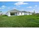 View of backyard featuring a lush green lawn and a modern house with sliding glass doors at 1596 Laurel Brook Ln, Port Charlotte, FL 33953