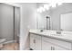 Modern bathroom featuring double sinks, white cabinetry, and wood-look tile flooring, with a view into the walk-in shower at 1596 Laurel Brook Ln, Port Charlotte, FL 33953