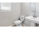Modern powder room with a pedestal sink, round mirror, and a window providing natural light at 1596 Laurel Brook Ln, Port Charlotte, FL 33953
