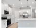 Modern kitchen boasts white cabinets, stainless steel appliances, and a spacious center island with pendant lighting at 1596 Laurel Brook Ln, Port Charlotte, FL 33953