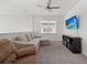 Living room features a television, comfortable couch, ceiling fan, and large windows at 16226 Paynes Mill Dr, Bradenton, FL 34211