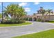 Elegant community clubhouse featuring a terracotta tile roof, lush landscaping, and convenient circular driveway at 2064 Batello Dr, Venice, FL 34292