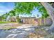 View of the backyard of this charming home with a partial wood fence, mature trees, and a mix of gravel and grass at 229 42Nd W St, Bradenton, FL 34209