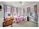 A sunny bedroom with a single bed, a ceiling fan and windows covered by lavender curtains at 229 42Nd W St, Bradenton, FL 34209