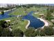 Aerial view of a beautiful golf course, featuring lush green fairways, palm trees, and serene water features with condo buildings in the background at 230 Sands Point Rd # 3501, Longboat Key, FL 34228