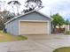 Detached one-car garage featuring a light-beige door and concrete driveway, surrounded by a well-maintained lawn and mature trees at 2309 30Th W Ave, Bradenton, FL 34205