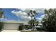 Charming single-story home featuring a two-car garage, well-manicured lawn, and mature palm trees against a partly cloudy sky at 23116 Amethyst Ave, Port Charlotte, FL 33952