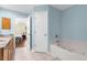 Bathroom featuring a large tub, double sink with granite counters, and entry to bedroom at 2396 Malibu Ln, North Port, FL 34286