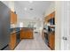 Modern kitchen with wood cabinets, granite countertops, stainless steel appliances, and ceramic tile flooring at 2396 Malibu Ln, North Port, FL 34286