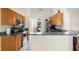 Open kitchen with wood cabinets, stainless appliances, and granite counters overlooks breakfast nook at 2396 Malibu Ln, North Port, FL 34286