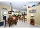 Open-concept dining area featuring a wooden table with bar seating, seamlessly connected to the kitchen at 24342 Saragossa Ln, Punta Gorda, FL 33955