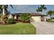 Charming home exterior with a well-manicured lawn and tropical landscaping at 24342 Saragossa Ln, Punta Gorda, FL 33955
