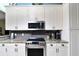 Well-lit kitchen with stainless steel oven, gray backsplash, granite countertops and white cabinets at 24342 Saragossa Ln, Punta Gorda, FL 33955