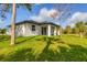 Back exterior view of home, with a lush green lawn and tropical palm trees at 299 Australian Dr, Rotonda West, FL 33947