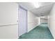 Hallway view featuring neutral walls and blue-green carpeting leading to various units and exit at 3006 Caring Way # 210, Port Charlotte, FL 33952