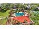 Aerial view of pool area with palm trees, lounge chairs and a clubhouse with a red roof at 3006 Caring Way # 210, Port Charlotte, FL 33952