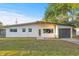 A charming, one-story home with a white exterior, gray trim and a well-manicured front lawn under a clear blue sky at 3169 Bellevue St, Sarasota, FL 34237
