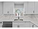 Well-lit kitchen featuring a stainless steel sink, white countertops, and sleek white cabinets at 3169 Bellevue St, Sarasota, FL 34237