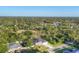Aerial shot of a home nestled among lush trees with a clear blue sky backdrop at 3694 Crittendon St, North Port, FL 34286