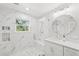 Bright bathroom featuring marble tiling in shower with built-in niche and seat, and vanity with round mirror at 4013 Red Rock Ln, Sarasota, FL 34231