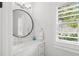 Bright bathroom features a round mirror above a vanity, natural light from a shuttered window at 4013 Red Rock Ln, Sarasota, FL 34231