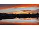Sunset view of homes reflected in a calm pond with vibrant clouds at 4136 Cascade Falls Dr, Sarasota, FL 34243