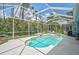 Screened-in pool area with clear blue water, spa, and comfortable seating surrounded by greenery at 4146 Westbourne Cir, Sarasota, FL 34238