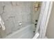 Bathroom with marble-look tiled walls and white bathtub with shower at 450 Gulf Of Mexico Dr # B207, Longboat Key, FL 34228