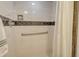 Close up on a shower with white tiling, grab bar, and a decorative tile accent at 450 Gulf Of Mexico Dr # B207, Longboat Key, FL 34228