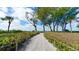 Scenic path leading to the beach, surrounded by lush greenery and clear blue skies at 4760 Gulf Of Mexico Dr. Villa 7, Longboat Key, FL 34228