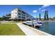 Condo building with boat dock and lift, lush lawn, and mature palm trees on a sunny day at 4760 Gulf Of Mexico Dr. Villa 7, Longboat Key, FL 34228