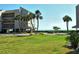 Beautifully landscaped exterior showcasing tropical trees and lush green grass near the waterfront at 4760 Gulf Of Mexico Dr. Villa 7, Longboat Key, FL 34228