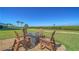 Cozy outdoor fire pit area with seating, perfect for relaxing and enjoying the green landscape at 4760 Gulf Of Mexico Dr. Villa 7, Longboat Key, FL 34228