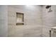 Elegant shower features stylish tile and built-in shelving for convenience at 4760 Gulf Of Mexico Dr. Villa 7, Longboat Key, FL 34228