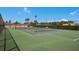 A green tennis court is enclosed in fencing and surrounded by green landscaping, with palm trees in the background at 5300 Gulf Dr # 204, Holmes Beach, FL 34217
