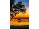 Scenic waterfront view of a dock and calm waters reflecting the sunset with some foliage in the foreground at 60 Liles St, Terra Ceia, FL 34250