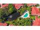 This aerial view shows a community pool, pond with fountain, and red tiled roofs surrounded by mature trees at 6407 Quail Hollow Pl, Bradenton, FL 34210