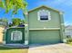 Two-story green home featuring an attached two-car garage and well-maintained landscaping at 7114 Hamilton Park Blvd, Tampa, FL 33615