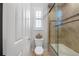 Bathroom features a white toilet, tan tile and glass enclosed bathtub with shower at 7709 Hazeltine Gln, Lakewood Ranch, FL 34202
