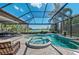 Screened-in pool area with a spa, lounge chairs and view of the golf course and lake at 7709 Hazeltine Gln, Lakewood Ranch, FL 34202