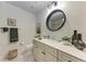 Bright bathroom featuring a vanity with a round mirror and forest-themed decor at 7710 Lake Vista Ct # 407, Lakewood Ranch, FL 34202