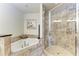 Elegant bathroom featuring a soaking tub and a glass-enclosed shower with decorative tile surround at 7710 Lake Vista Ct # 407, Lakewood Ranch, FL 34202