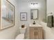 Chic half-bathroom with wooden vanity, a single sink, and tasteful nature-themed artwork at 7710 Lake Vista Ct # 407, Lakewood Ranch, FL 34202