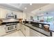 Bright kitchen features stainless steel appliances, black countertops, and light cabinets overlooking the living room at 7710 Lake Vista Ct # 407, Lakewood Ranch, FL 34202