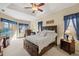 This main bedroom has a tray ceiling, ceiling fan, and large windows letting in lots of natural light at 8271 47Th Street E Cir, Palmetto, FL 34221